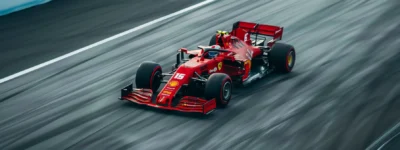 a sleek, vibrant red formula 1 car zooming down a racetrack at top speed.